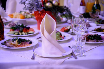 A festive table with a white tablecloth, snacks, and glasses