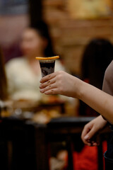 A woman's hand holds an alcoholic cocktail in a glass garnished