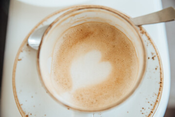 Close-up of coffee grounds in a white cup on a saucer with a spoon, top view