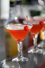 Bright red alcoholic cocktail with cherry on the bar counter with reflections