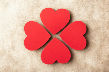 Four red hearts arranged in a clover shape on a textured background