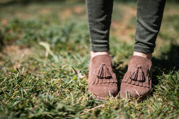 Stylish suede moccasins with tassels stand out against the green grass, perfect for lifestyle blog or fashion magazine promoting fall trends