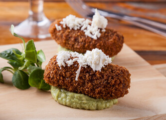 A croquette filled with cheese and spices, breaded with Japanese bread and served on guacamole.