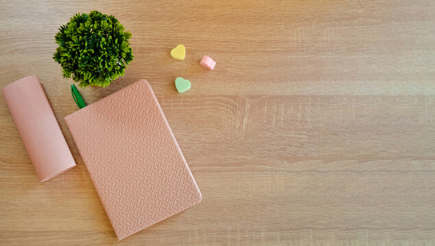 On the wooden surface of the table there is a notebook with a pen and elastic bands