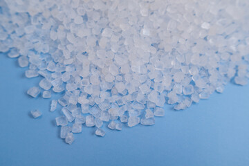 Close-up of white, translucent sugar crystals scattered on a blue textured fabric, food and beverage ingredient, abstract culinary background and food texture design