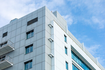 A modern building with a curtain-wall ventilated facade made of porcelain stoneware. Clean lines, white paint, large windows, and balconies. Contemporary style.