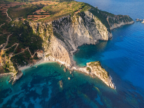 Aerial view of the rugged cliffs meeting the turquoise waters at Petani beach, creating a breathtaking contrast of textures and tones, Paliki, Kefalonia, Greece.
