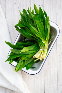 Fresh wild garlic bunch on white wooden background