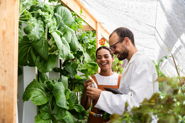 Scientists analyzing plants in aquaponic greenhouse with tablet