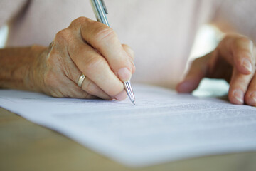 Hand signing retirement paper and financial document indoors