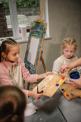 Art lesson. Kids draw pictures in art class. Childs enjoy painting in workshop. Group of school children drawing with brush landscapes on easel. Education and learning concept. Mix and combine colors.