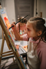 Childs enjoy painting in workshop. Art lesson. Kids draw pictures in art class. Group of school children drawing with brush landscapes on easel. Education and learning concept. Mix and combine colors.