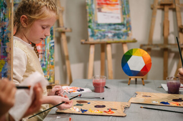 Girl mixed and combined colors. Education and learning concept. School kid drawing with brush on easel. Girl enjoys painting in a workshop. Art lesson. Children drew a picture in art class. Closeup.