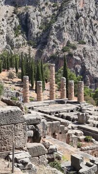 Ancient stone columns and ruins of the Temple of Apollo at Delphi, Greece. Historic archaeological, Mount Parnassus, surrounded by rocky cliffs and cypress trees. famous for the Oracle of Delphi.