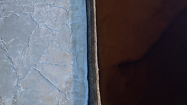 Aerial view of a stark contrast between cracked earth and a dark body of water creating a mesmerizing visual divide, Sunnyvale, California, United States.