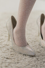 Naklejka premium a little girl's feet in high heels that are too big for her
