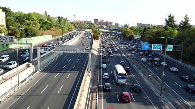 4K horizontal shot from bridge overlooking heavy traffic on Madrid M30 highway with central lanes and service roads jammed on a clear Thursday afternoon