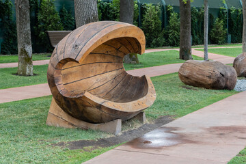 Public landscape 'Galitsky park' for relaxation and walking. This outdoor sculpture features a large, intricately carved wooden bench resembling a curved, abstract form, surrounded trees and pathways.