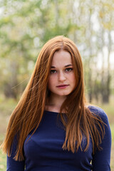 Obraz premium Redhead Long Auburn Hair Young Woman in Navy Top Standing in Yard Looking at camera