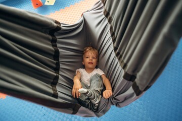 Lying down in the hammock. Cute preschool child, boy, during developmental activities in a playroom