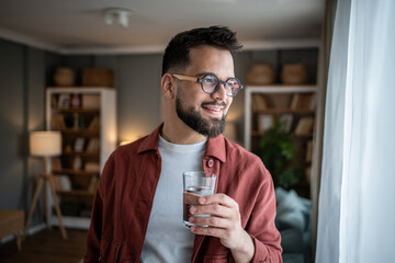 Young man holding glass of water at home