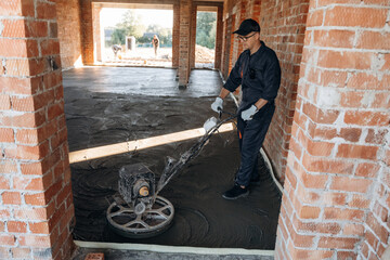 Fototapeta premium Holding the device for leveling the floor, concrete. Builder is working on construction site, unfinished building
