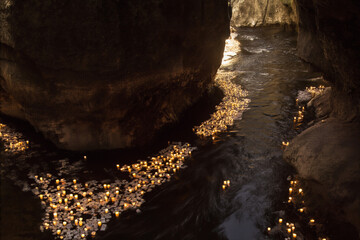 Floating Candles Drifting Through Narrow Rock Canyon Stream