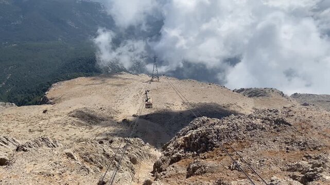 The cable car approaches through clouds and cliffs, selective focus. A must-see experience for mountain explorers