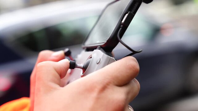 Side view of operator hands managing drone flight using modern remote controller with smartphone display, highlighting precision joystick control and professional UAV navigation setup