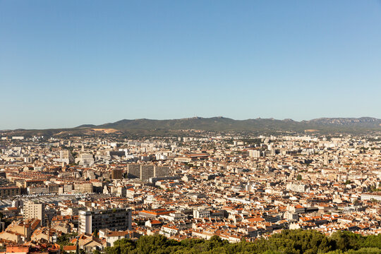 Panorama sur la ville de Marseille, vue sur les toits de la ville vers le Vieux-Port et les collines du Massif de l'&Eacute;toile, ciel bleu en arri&egrave;re plan