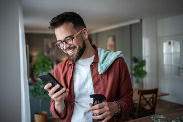 Man smiling using smartphone while taking a cleaning break