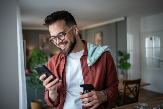 Man smiling using smartphone while taking a cleaning break