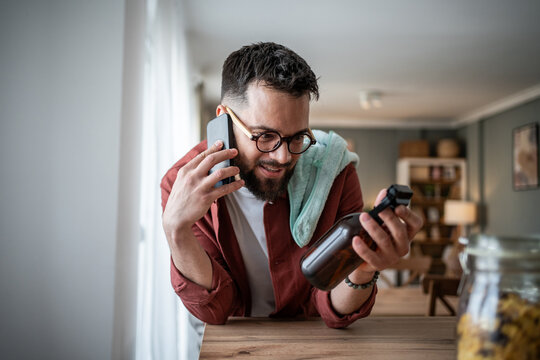 Man multitasking having phone call while cleaning home