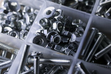 Fototapeta premium Close up of an organizer box filled with collection of metal hardware. Various steel screws, nuts, bolts, and washers for construction, repair, or DIY projects