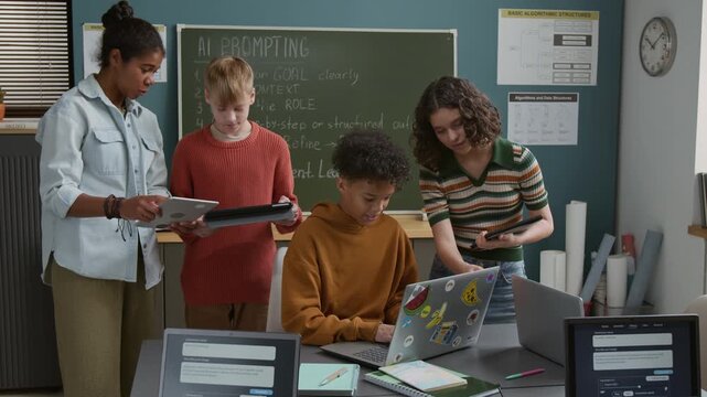 Medium shot of four multiethnic teenage students working on artificial intelligence projects. African American girl demonstrating code on tablet to Caucasian boy, two schoolkids typing on laptop