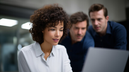 Colleagues gathered around laptop discussing business strategy, multicultural office team cooperating on project, concept of leadership, teamwork and innovation in modern workplace
