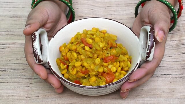 hand holding serving bowl filled with lauki chana dal ki sabji (bottle gourd lentil curry). pure vegetarian dish eaten on the first day of Chhath Puja. 