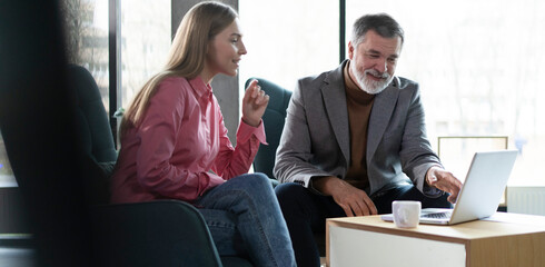 Two business partners checking document working together on laptop computer in office at corporate...