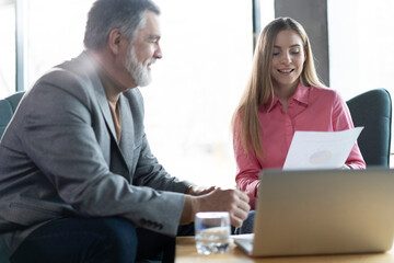 Two colleagues of the company, woman and mature man, working together on a new project in modern office