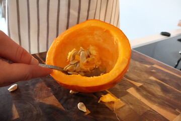 Chef scrapes the seeds from a Hokkaido pumpkin, cooking preparation, autumn vegetable and culinary process, perfect for thanksgiving