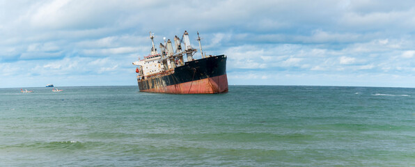A view of the sea and clear autumn sky where an old cargo ship is anchored