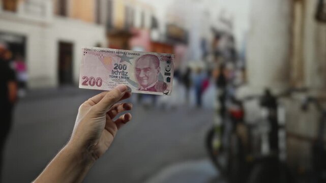Man holding turkish lira banknote on city street highlighting urban exchange scene vibrant with local life and commerce.
