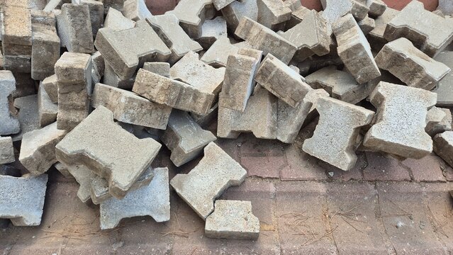 random pile of gray interlocking pavers. I-shaped interlocking paving stones - Powered by Adobe