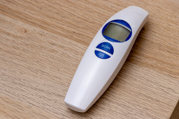 A digital thermometer resting on a wooden surface, designed for quick temperature measurements. Ideal for healthcare settings, home use, or medical devices.