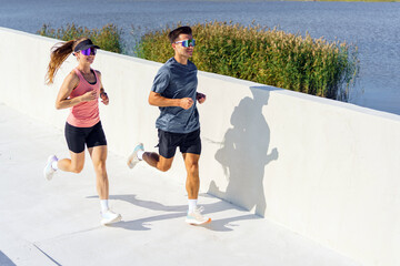 Couple jogging along a waterfront path in sunny weather