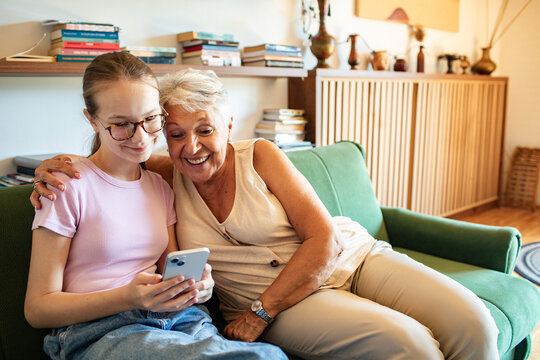 Senior woman and granddaughter using smartphone at home