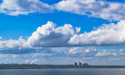 Industrial power plant by lake under blue sky