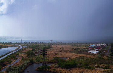 Heavy rain over the lake and a field with houses and power lines