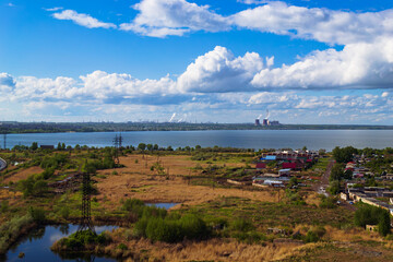 Power plant by lake under bright beautiful clouds