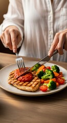 Person Cutting Grilled Chicken with Vegetables for a Healthy Meal.